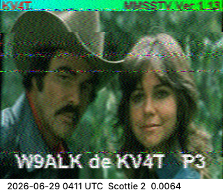 A decoded SSTV image: a color photo of Burt Reynolds and Sally Field, banded with the slant and noise typical of a slow-scan transmission, overlaid with the callsigns W9ALK de KV4T and the Scottie 2 mode.